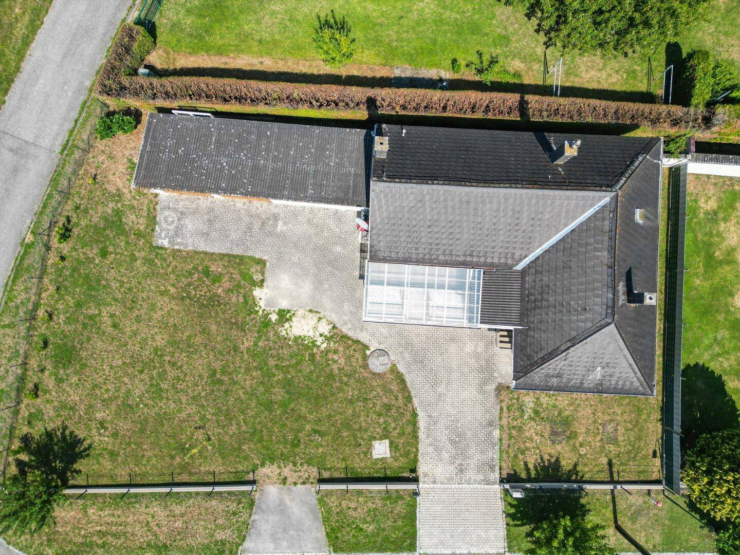 Luftaufnahme des Anwesens mit Haus, Garage, Garten und gepflasterter Zufahrt.