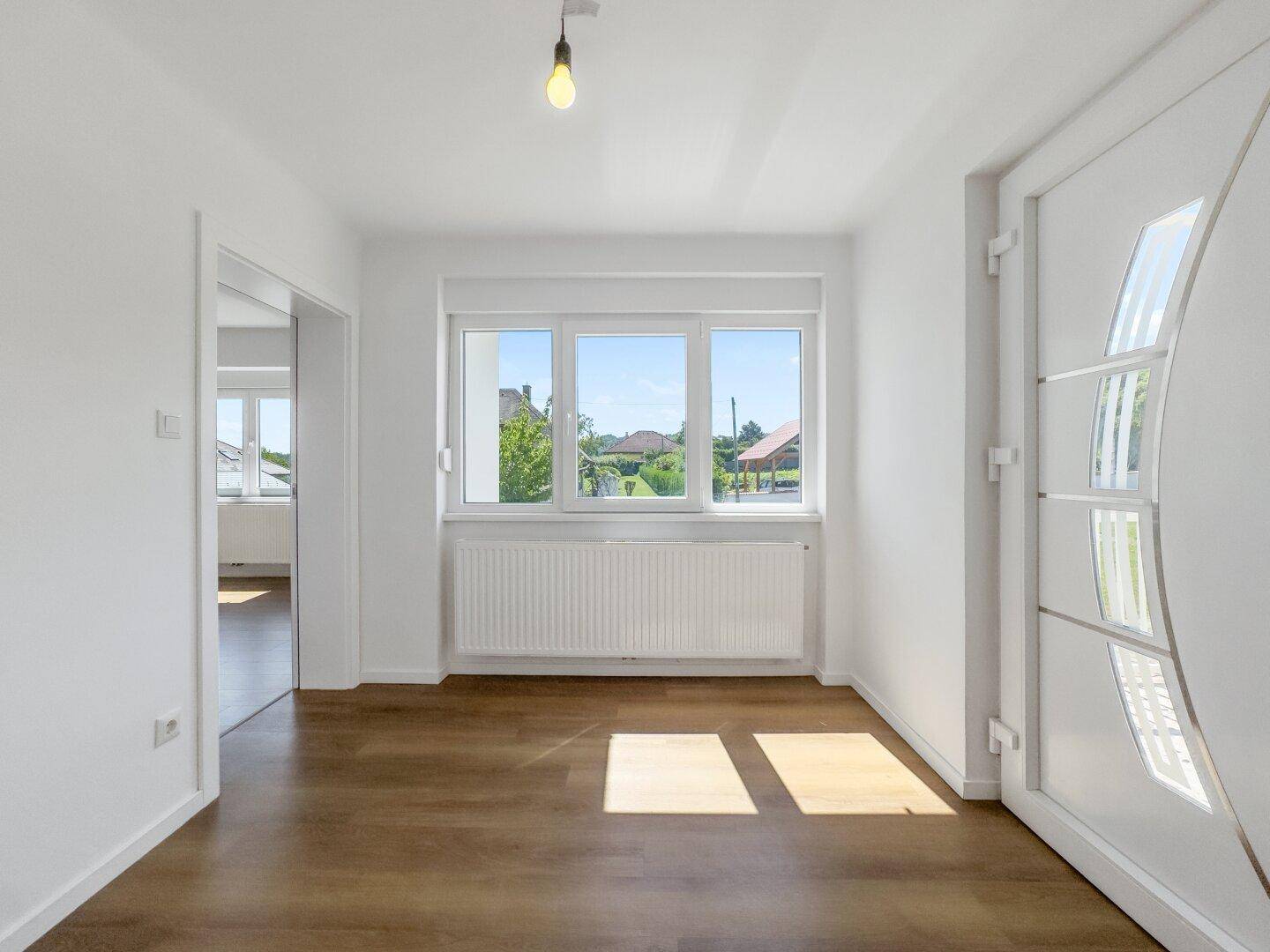 Heller Eingangsbereich mit Laminatboden und großer Fensterfront, die den Raum erhellt.