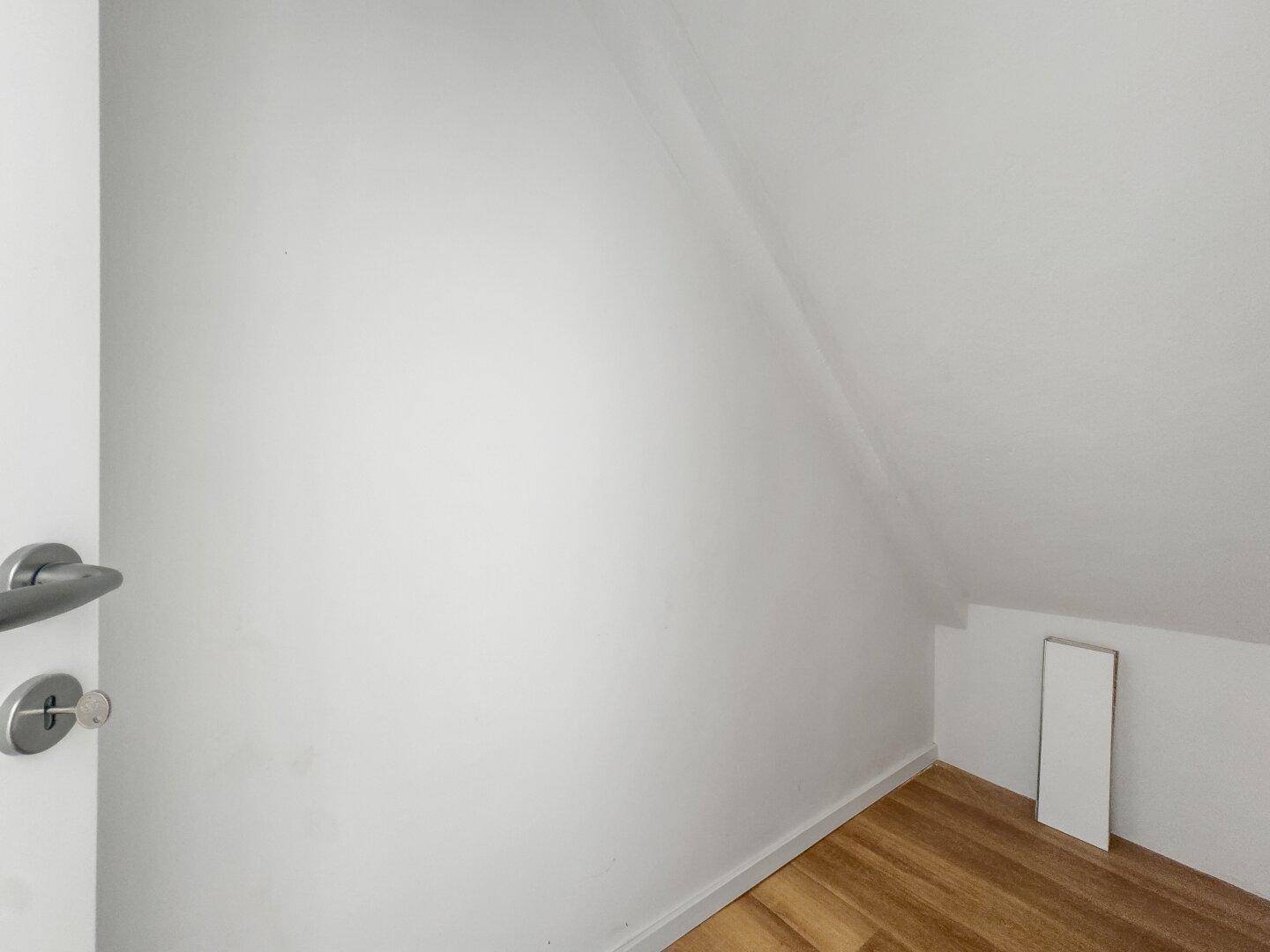 Kleiner Abstellraum im Dachgeschoss mit schräger Decke und Laminatboden.