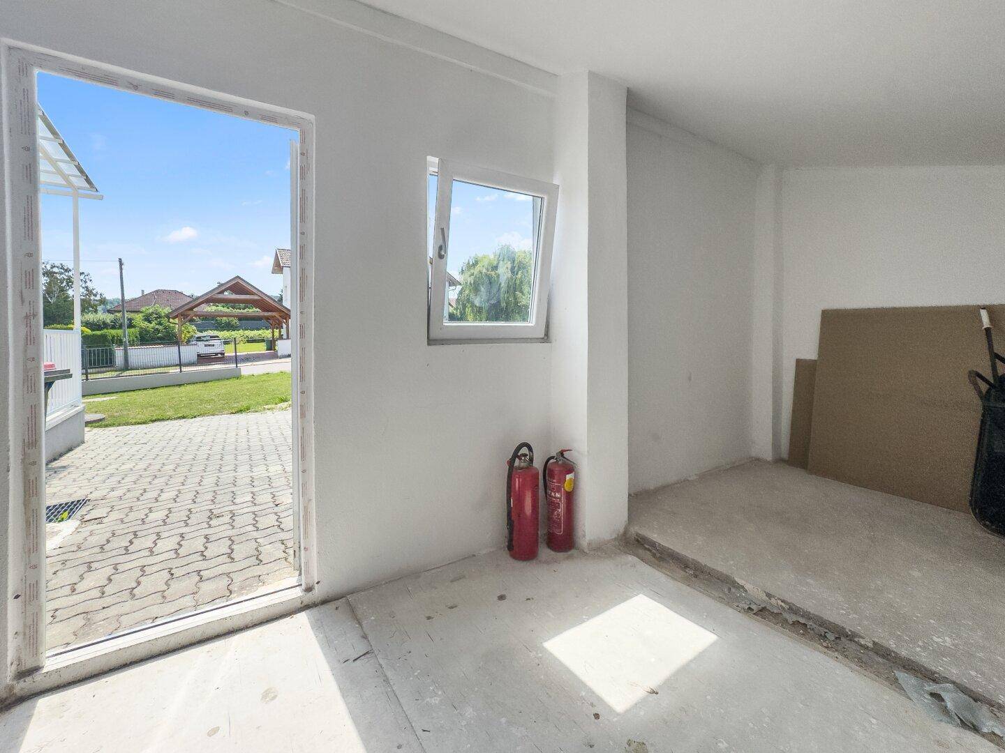 Geräumige Garage mit Betonboden, Fenster und Blick auf die Einfahrt.