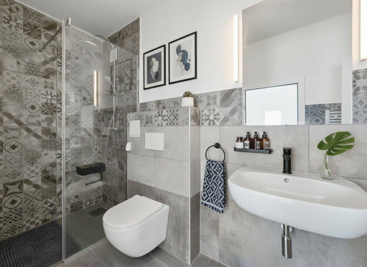 Modernes Badezimmer mit begehbarer Dusche, Wand-WC und stilvollen Fliesen.