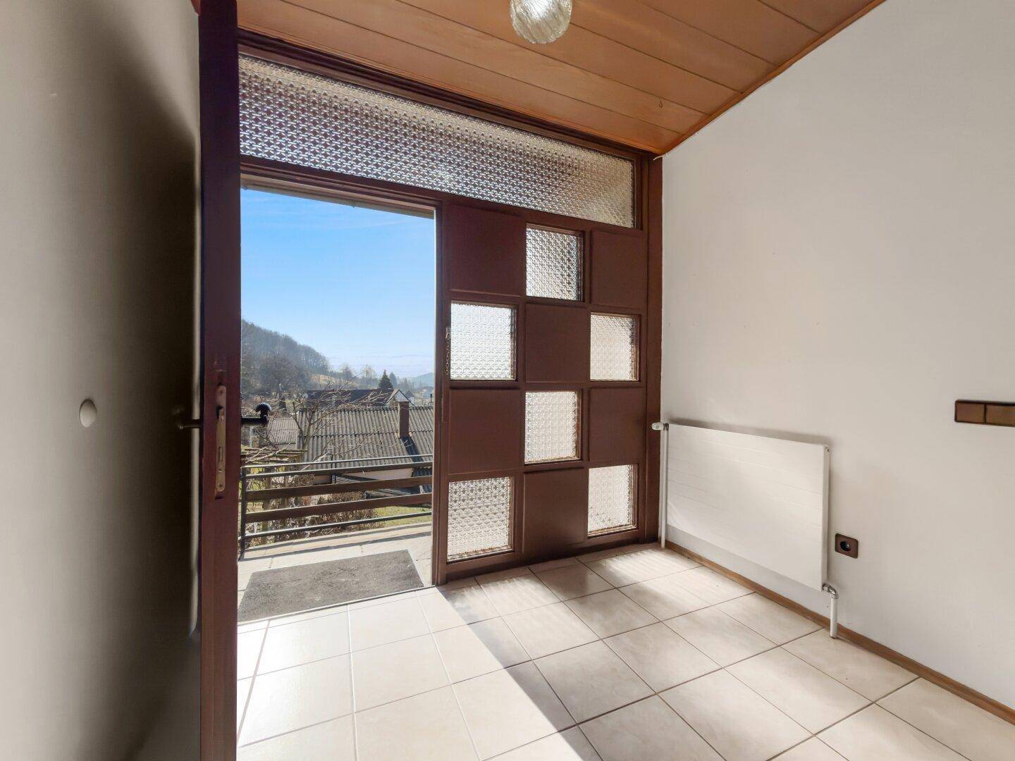 Eingangsbereich mit Fliesenboden und Zugang zu einem Balkon mit Weitblick.