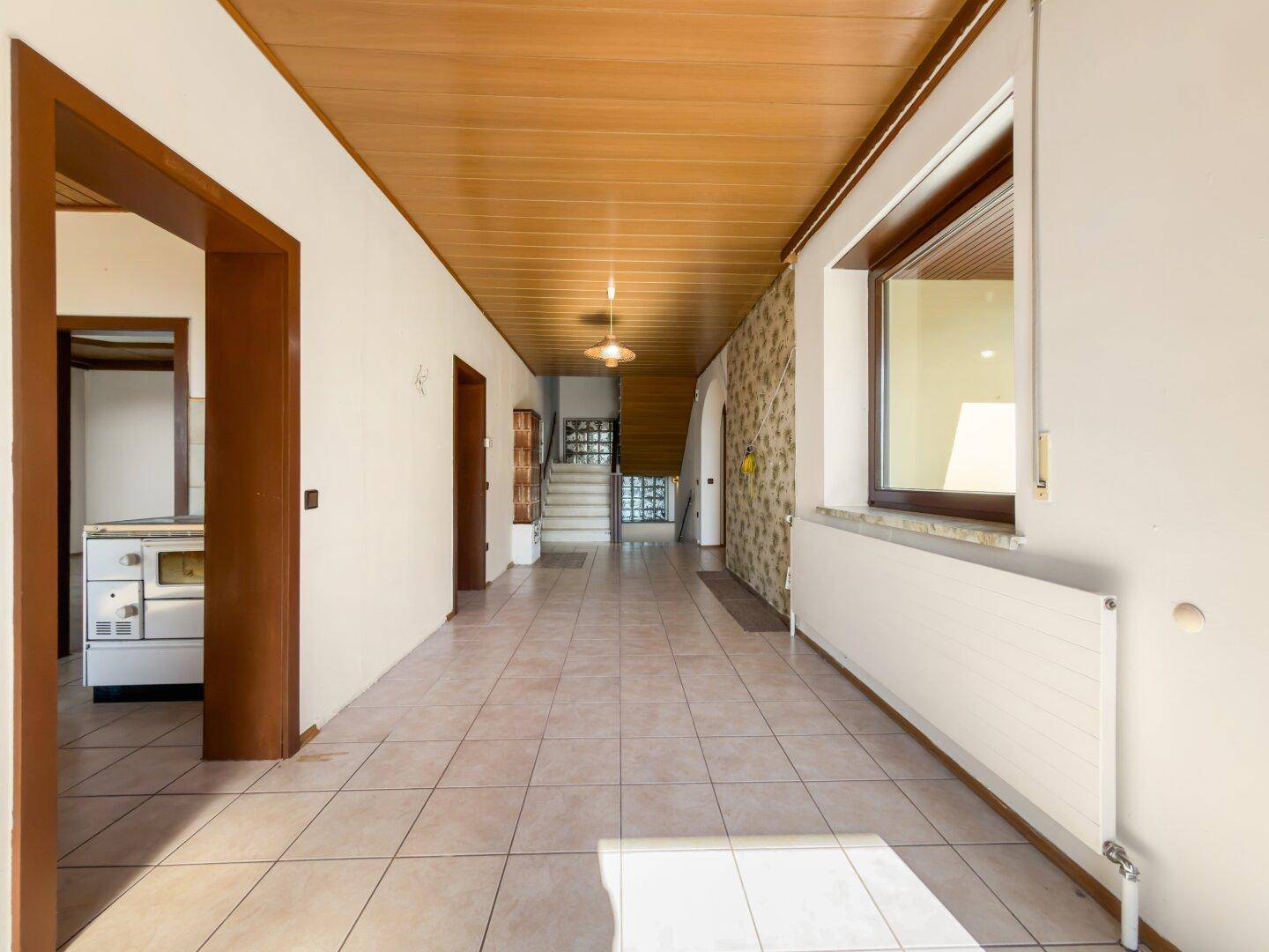 Geräumiger Flur mit Holzdecke, Fliesenboden und Zugang zu weiteren Räumen.