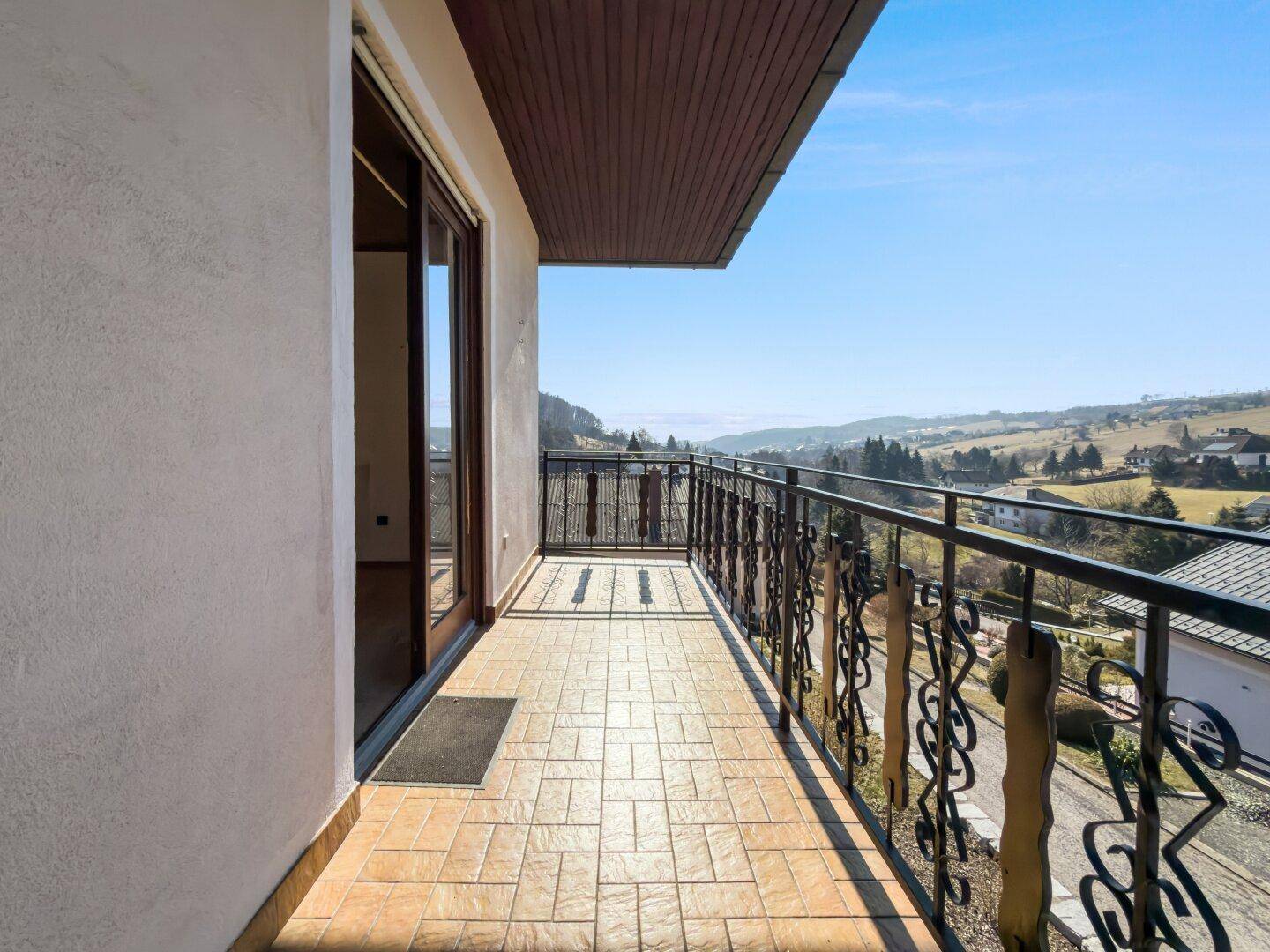 Großer Balkon mit schmiedeeisernem Geländer und weitem Blick über die Landschaft.