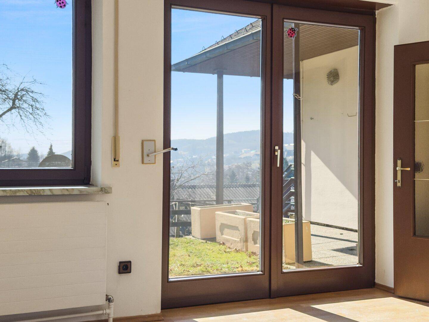 Blick durch eine Glastür auf den Außenbereich mit grüner Umgebung.