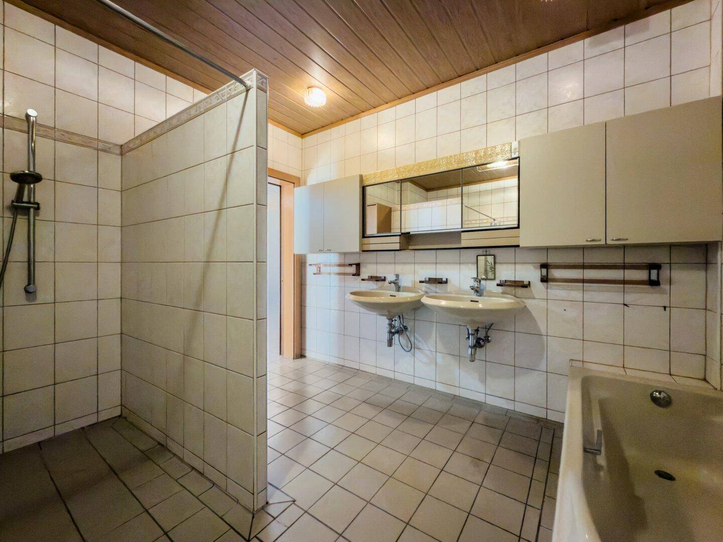 Badezimmer im Stil der 80er Jahre mit Doppelwaschbecken, Dusche und Badewanne.