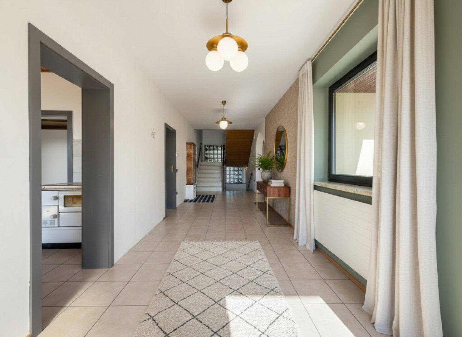 Heller Flur mit Fliesenboden, modernen Leuchten und Blick auf die Treppe.