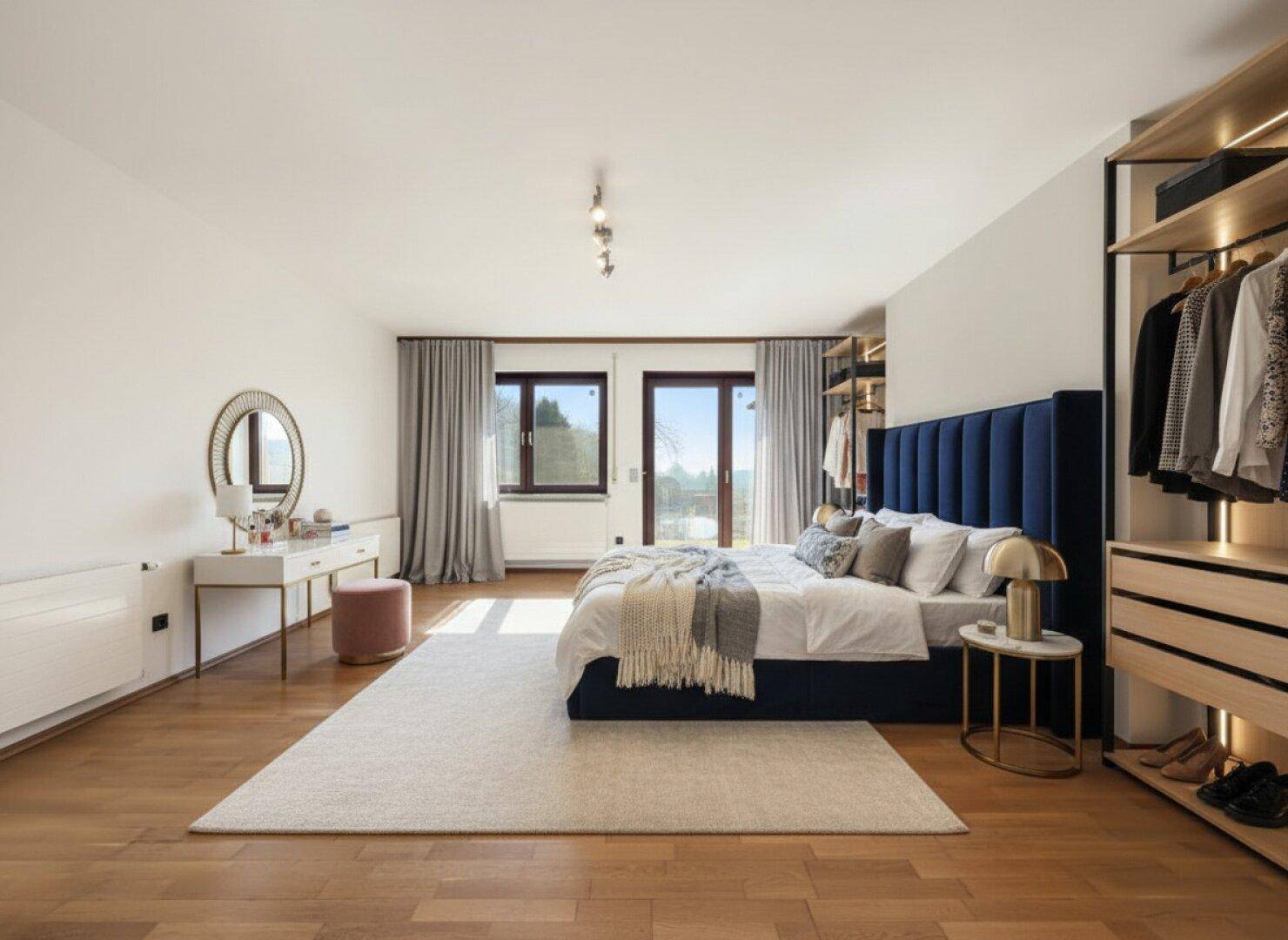 Geräumiges Schlafzimmer mit Parkettboden, begehbarem Kleiderschrank und Balkonzugang.