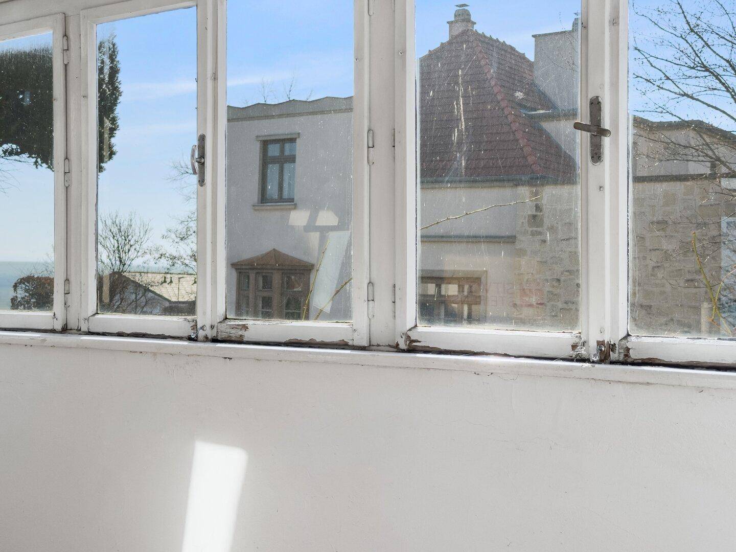 Detailansicht der Fensterfront eines Wintergartens mit Blick auf die Umgebung, sonnig und weitläufig.