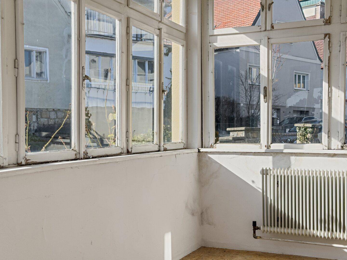 Detailansicht der Fensterfront eines Wintergartens mit Blick nach draußen, hell und offen.