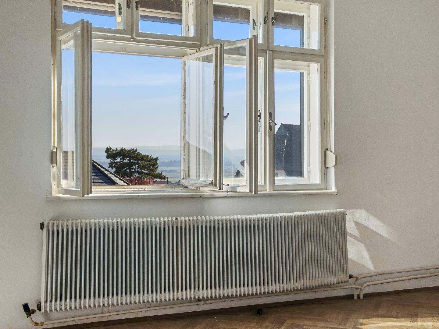 Geöffnetes Fenster in einem hellen Raum mit Blick auf die weite Landschaft, frische Luft und Aussicht.