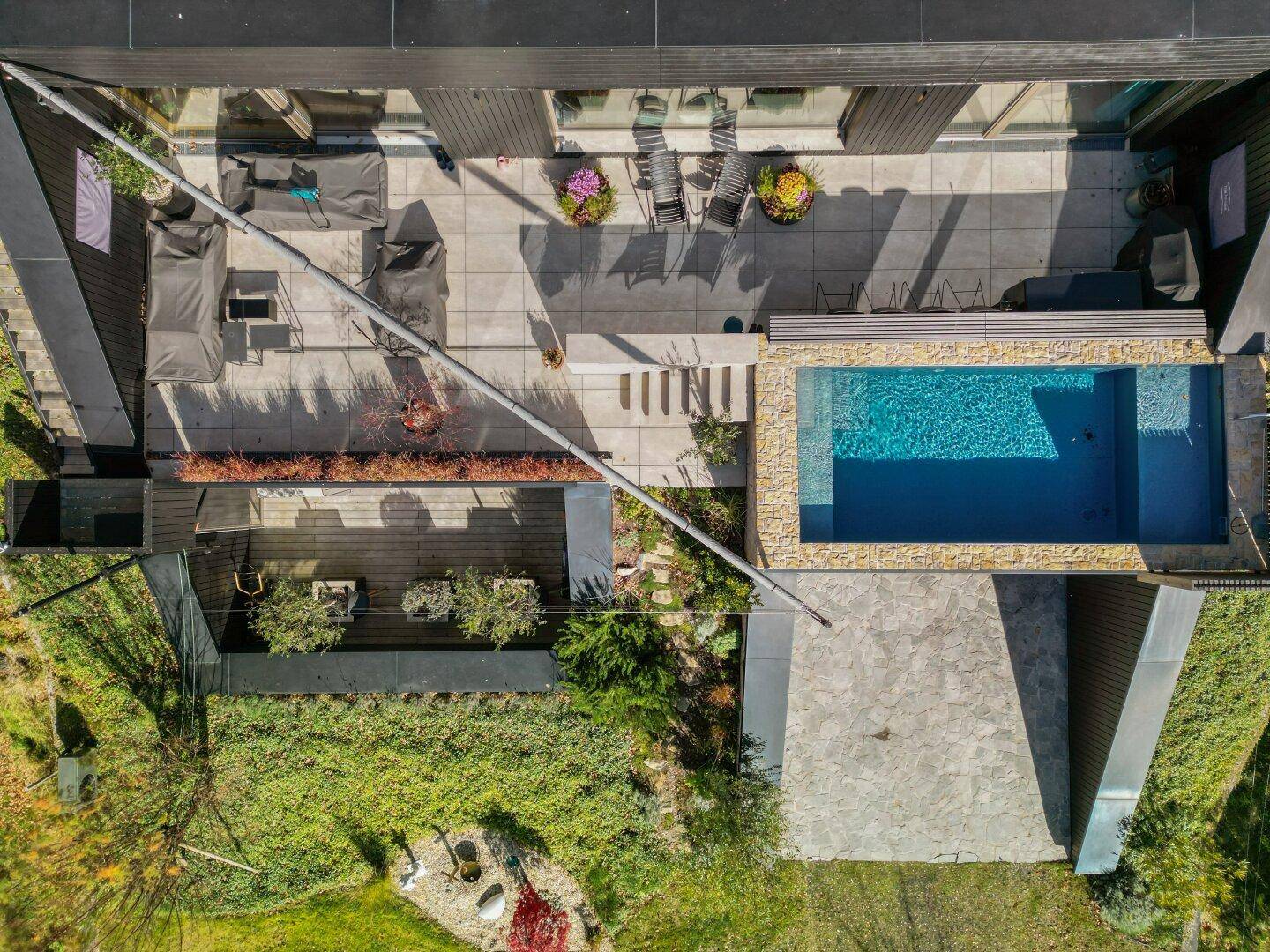 Draufsicht auf die moderne Villa mit Pool, großer Terrasse und Gründach.