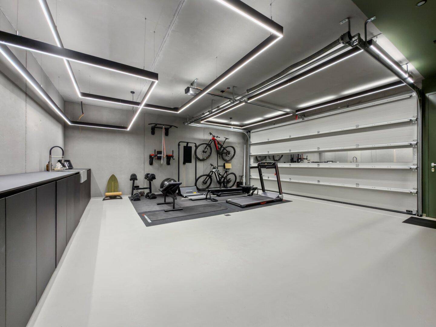Geräumige Garage, umfunktioniert als Fitnessraum mit Sportgeräten und Fahrrädern.