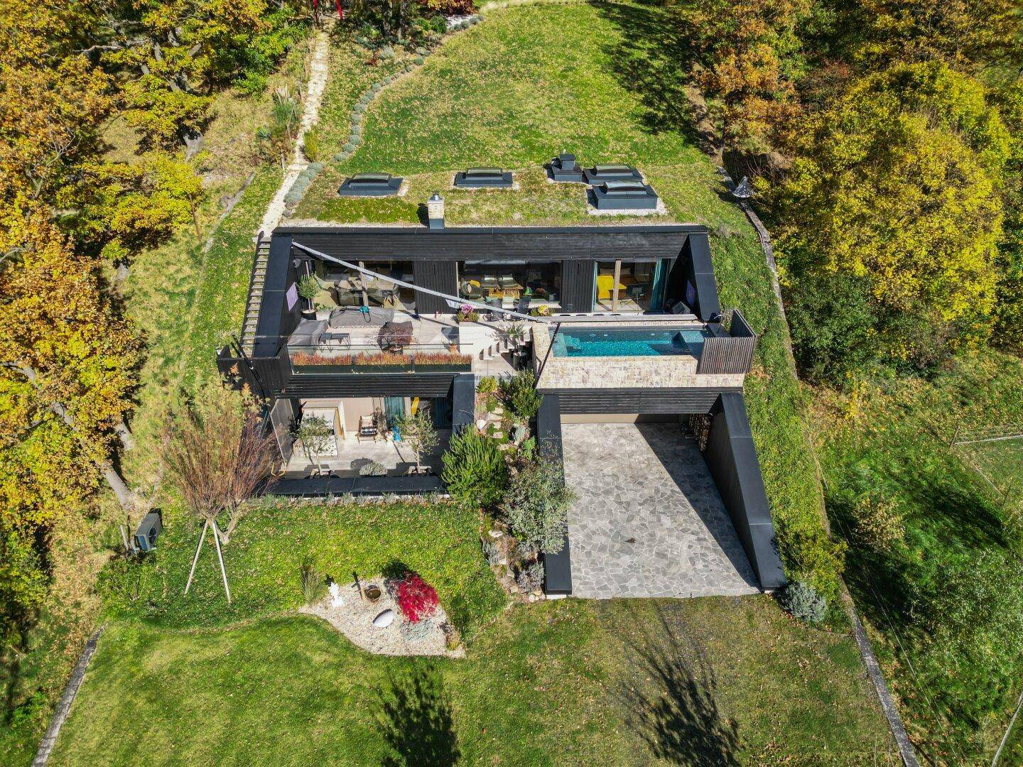 Moderne Villa mit Gründach, Infinity-Pool und weitläufigem Grundstück in grüner Umgebung.