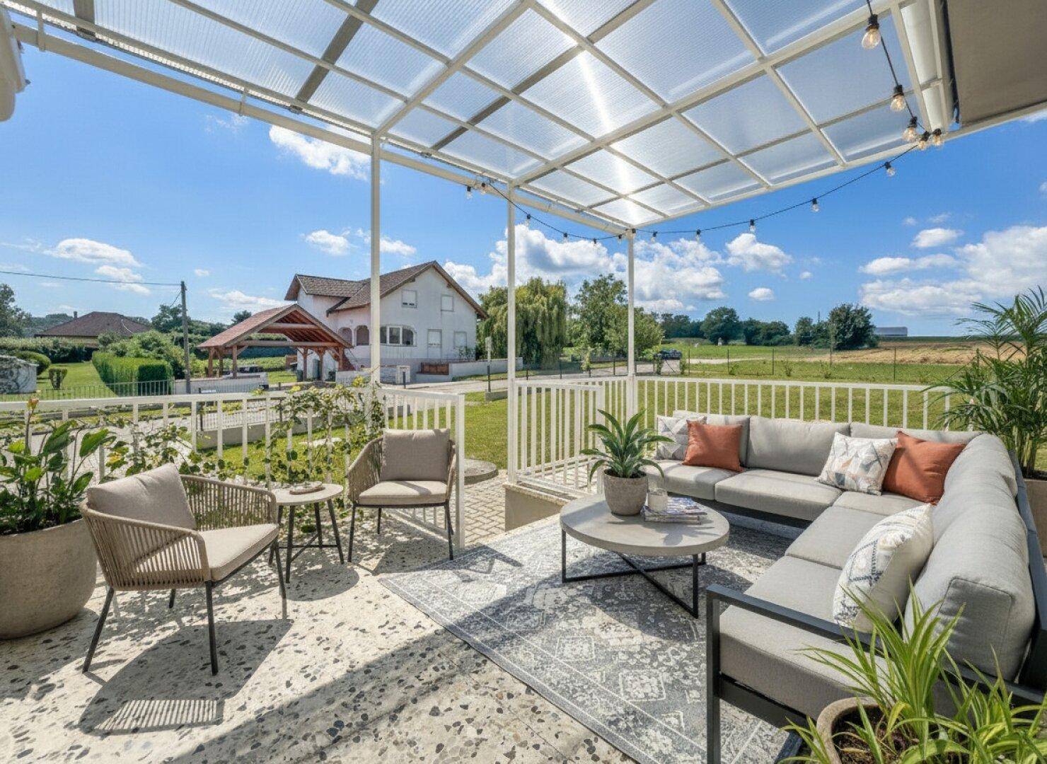 Gemütliche überdachte Terrasse mit modernen Gartenmöbeln und Blick ins Grüne.