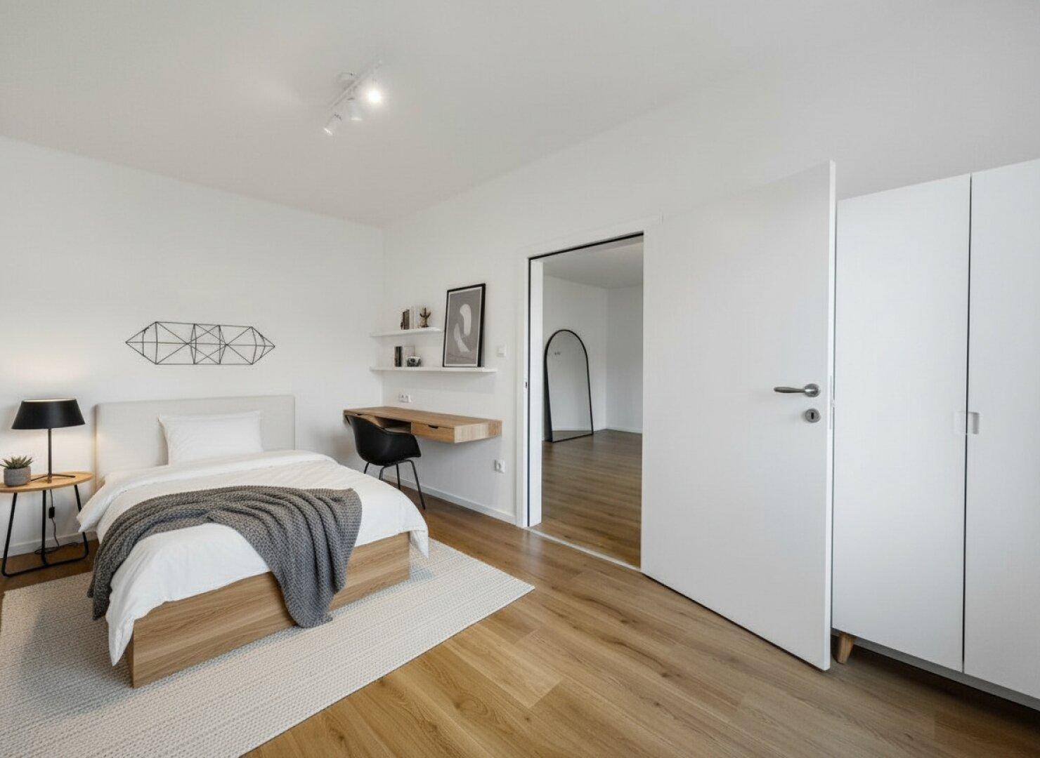 Modernes Schlafzimmer mit Holzboden, Bett und Schreibtisch, ideal für Home-Office.