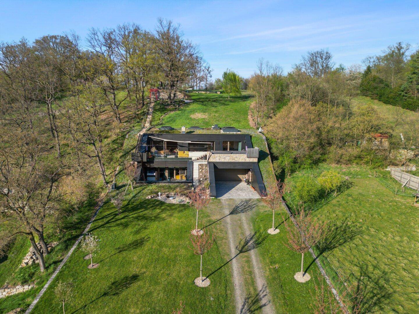 Luftaufnahme der modernen Villa mit Gründach und weitläufigem Grundstück.