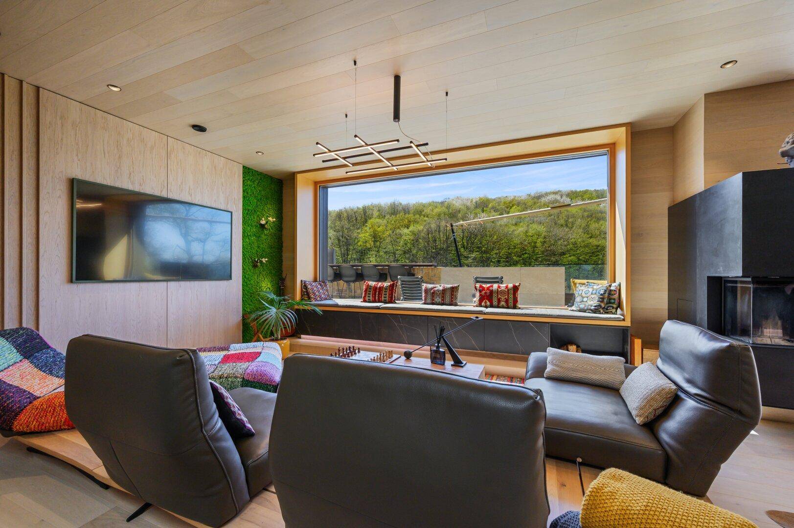 Wohnzimmer mit bequemen Sesseln, großem Fenster und Blick auf die grüne Landschaft.