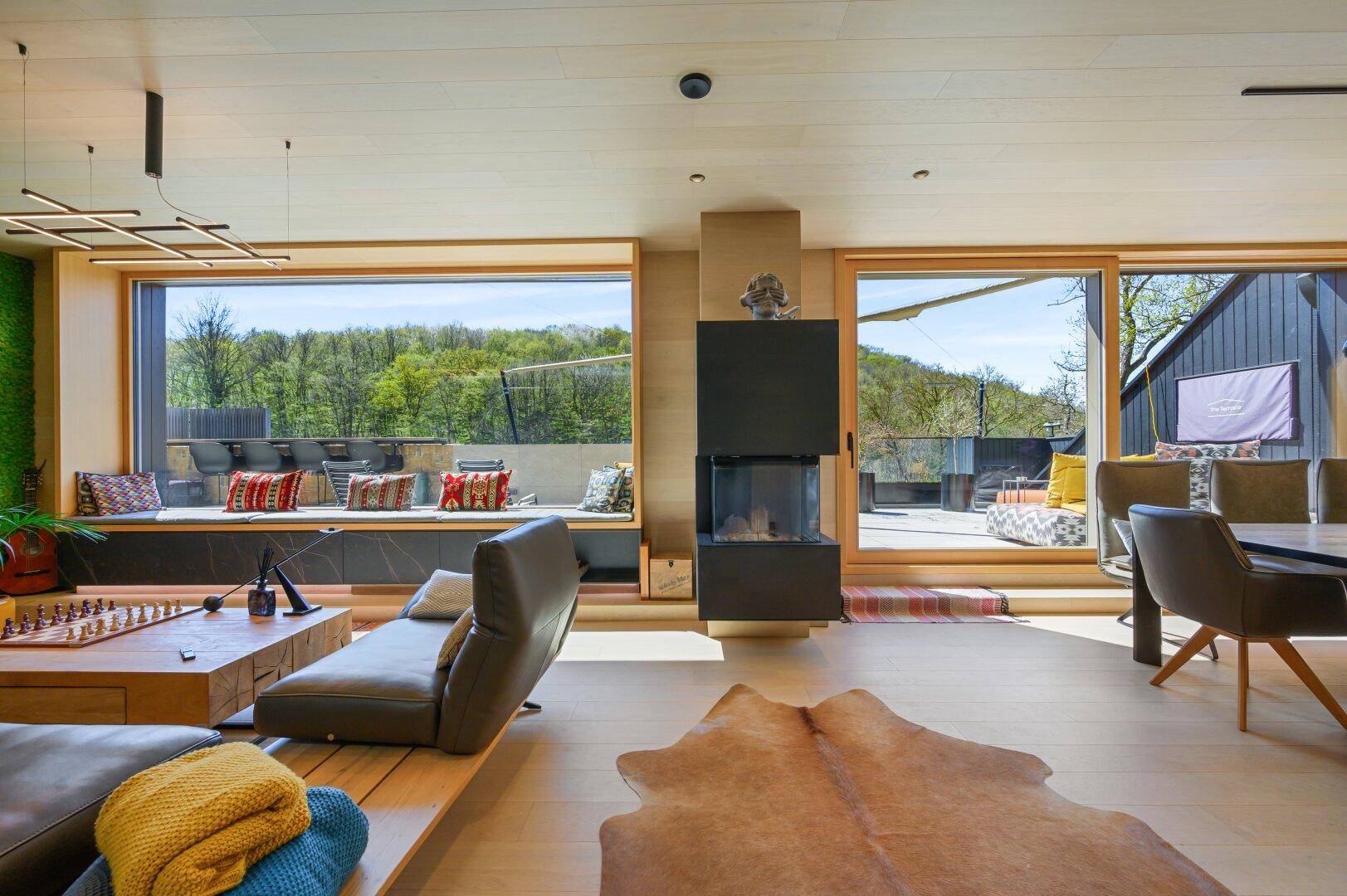 Moderner Wohn-Essbereich mit Holzboden, Kamin und Zugang zur Terrasse.