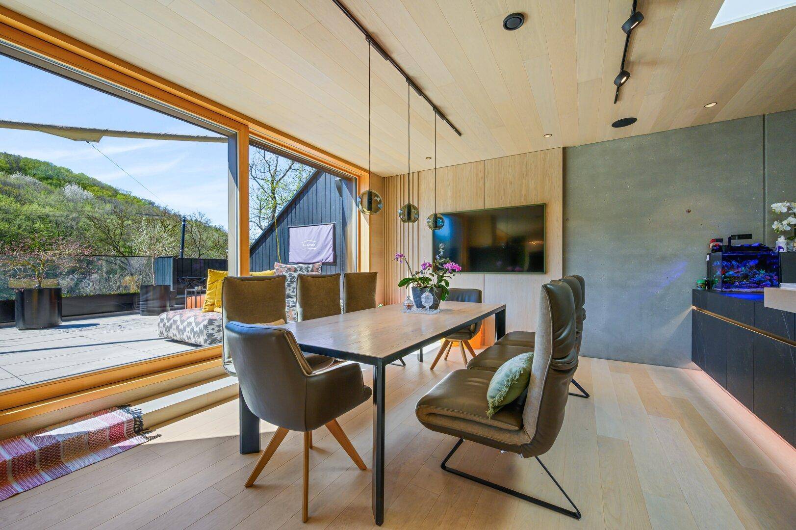Eleganter Essbereich mit Holzboden, großem Esstisch und Blick auf die Terrasse.