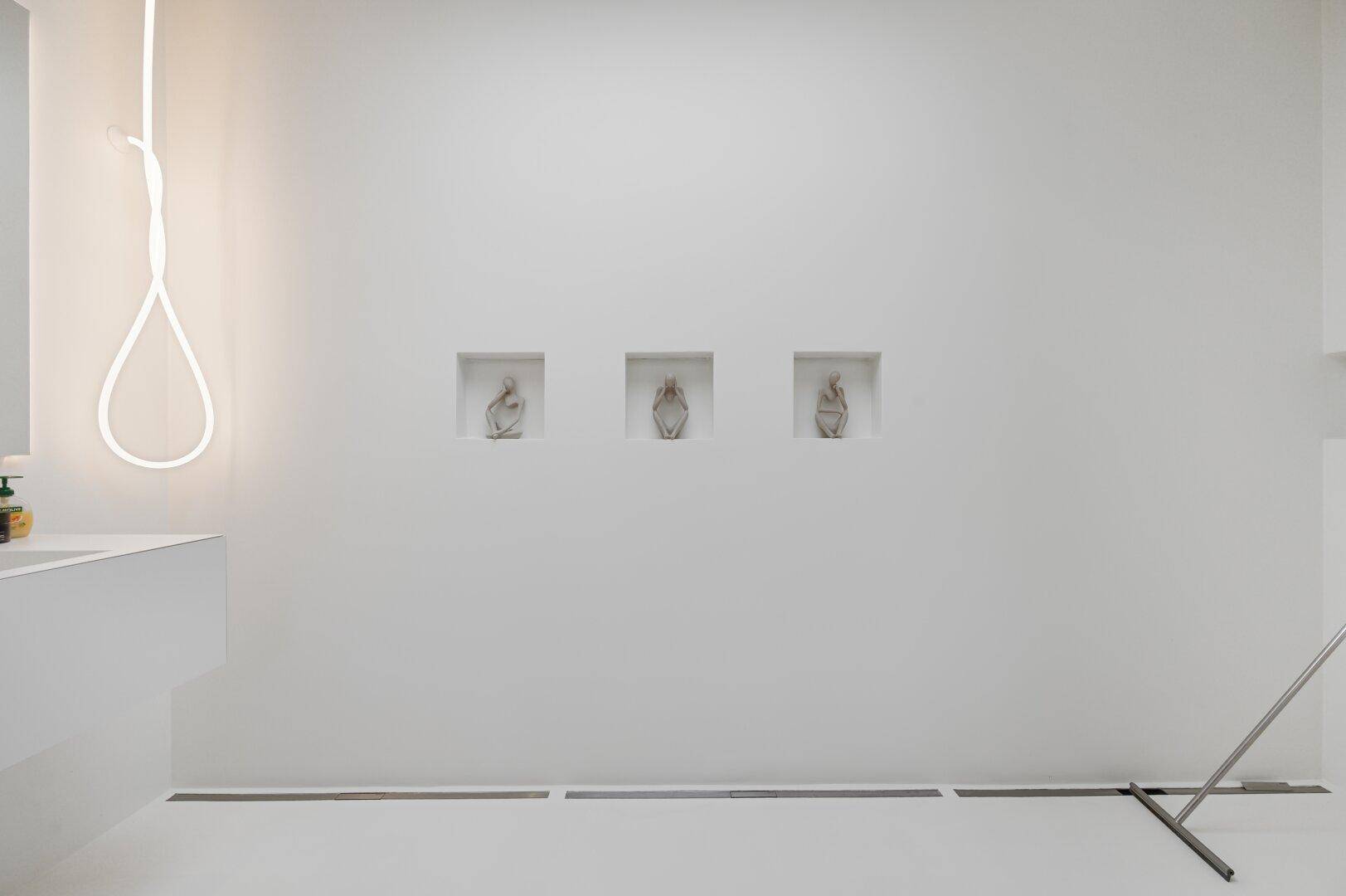 Minimalistische Badezimmerwand mit Nischen und weißer Farbgebung.