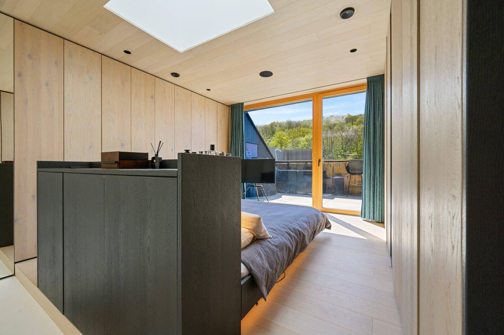 Schlafzimmer mit Holzboden, Einbauschränken und Blick auf die Terrasse.