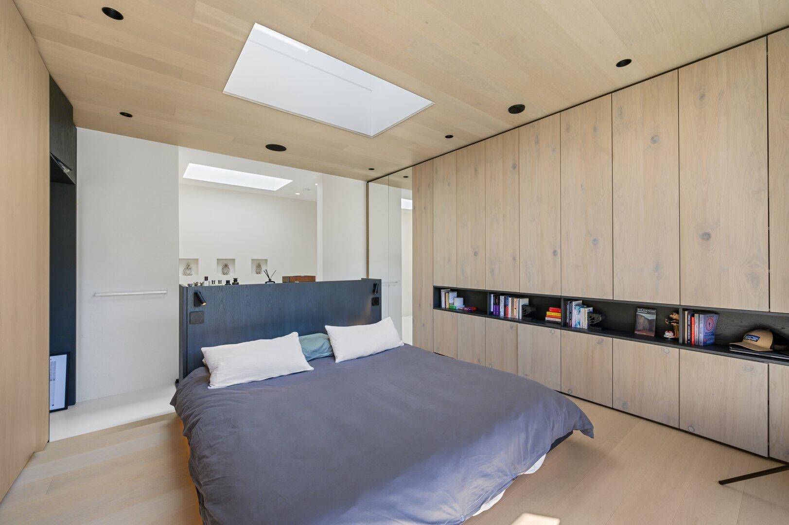 Helles Schlafzimmer mit Holzboden, Einbauschränken und Oberlicht.