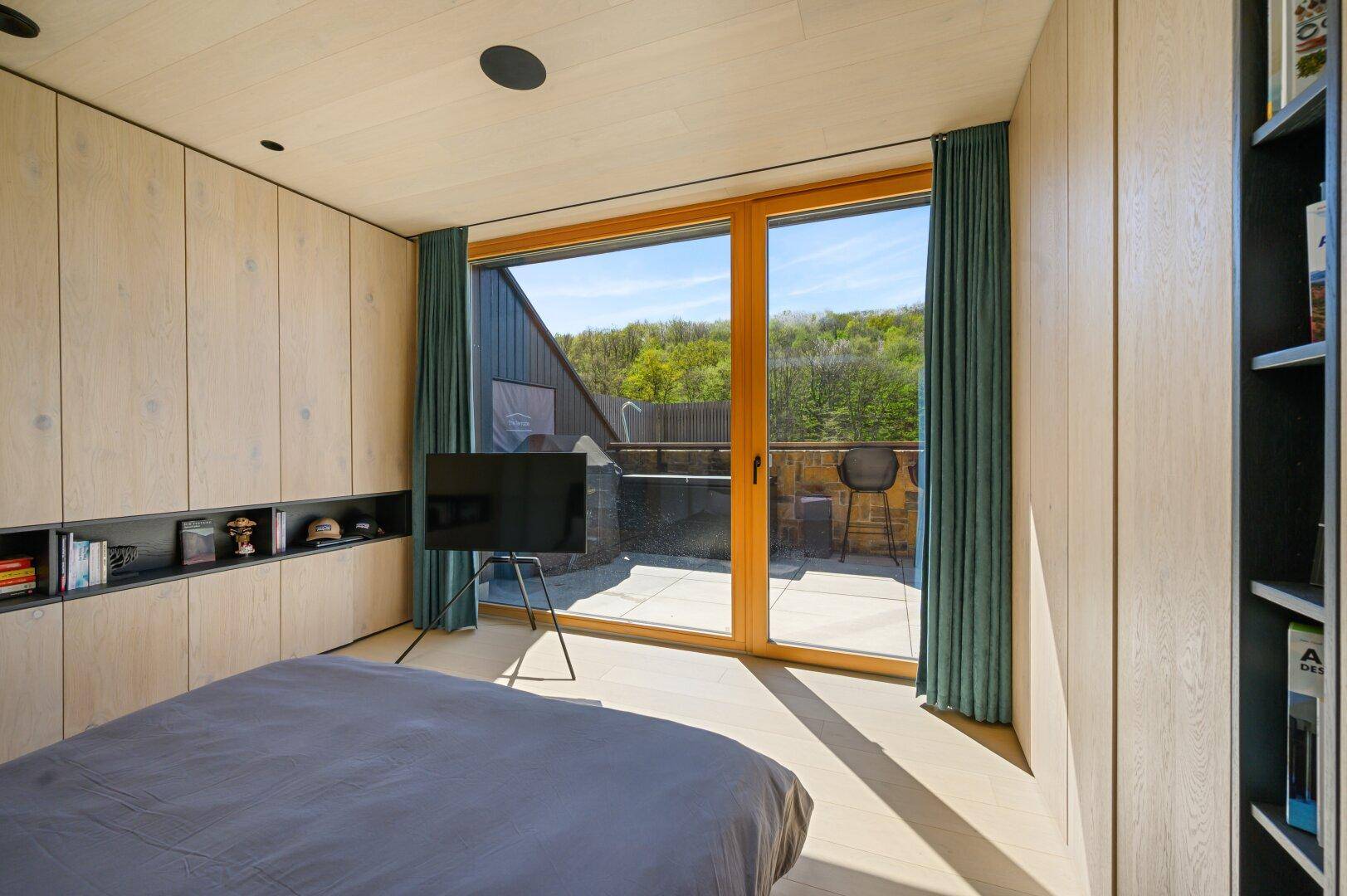 Schlafzimmer mit Holzboden, Einbauschränken und Zugang zur Terrasse.
