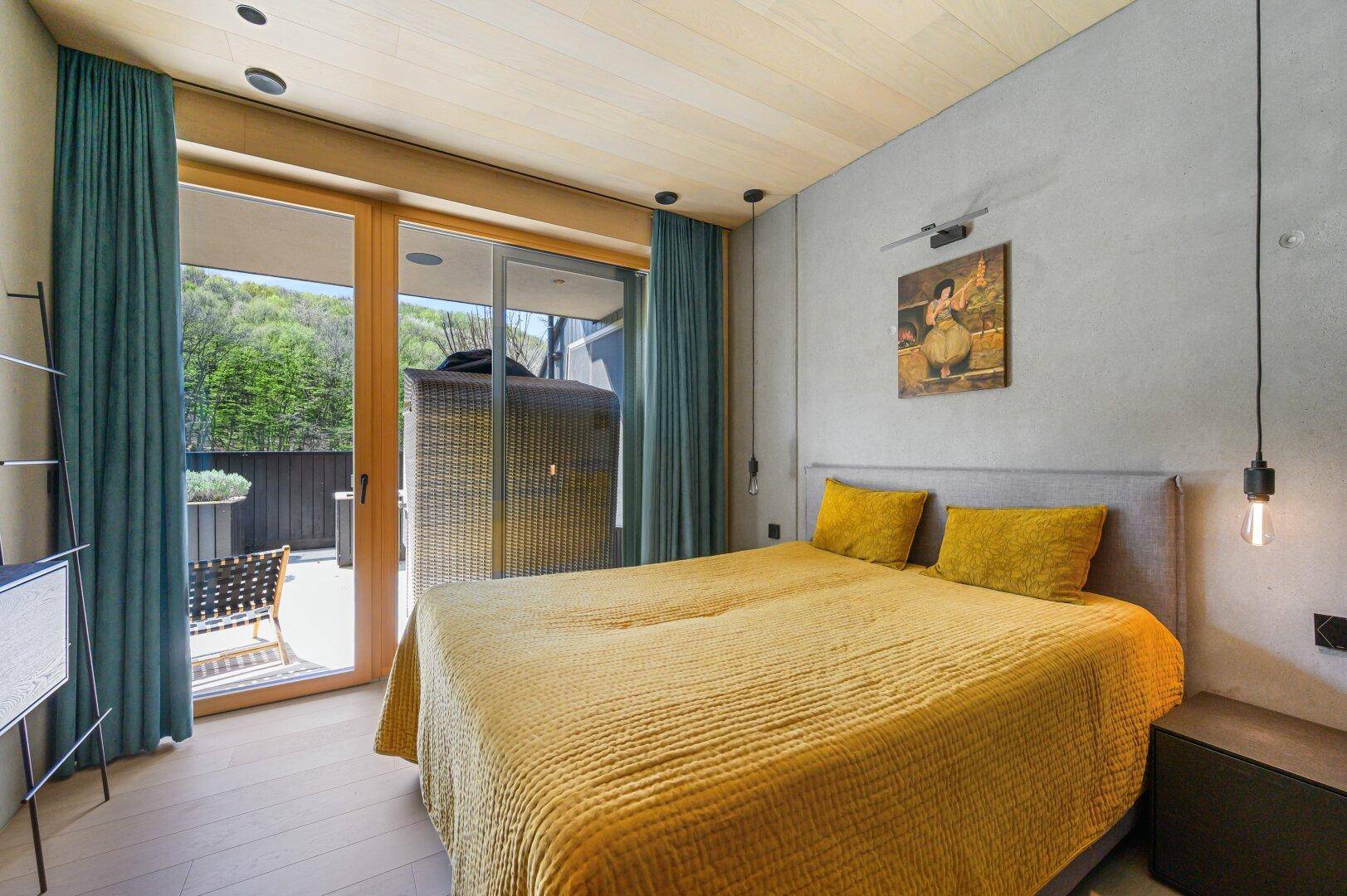 Helles Schlafzimmer mit Holzboden, großen Schiebetüren und Zugang zur Terrasse.