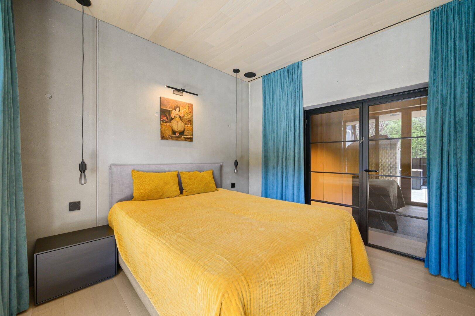 Modernes Schlafzimmer mit Holzboden, Einbauschränken und farbigen Vorhängen.