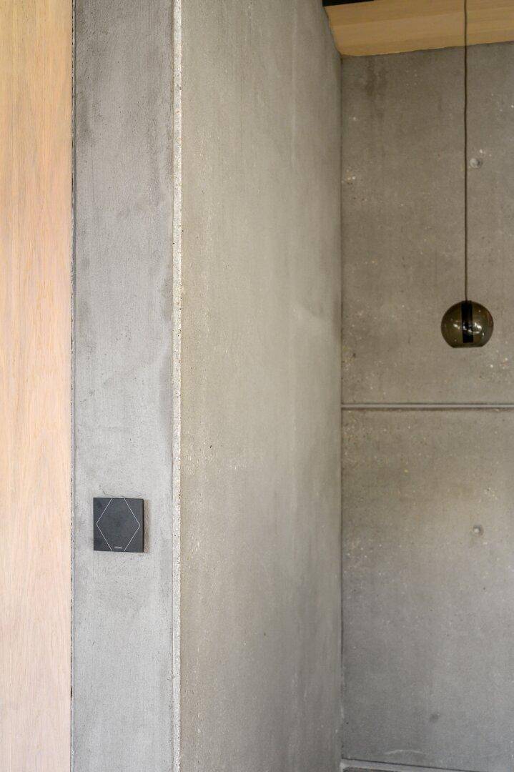 Detailansicht einer modernen Wand mit Holzelementen und Schalter.