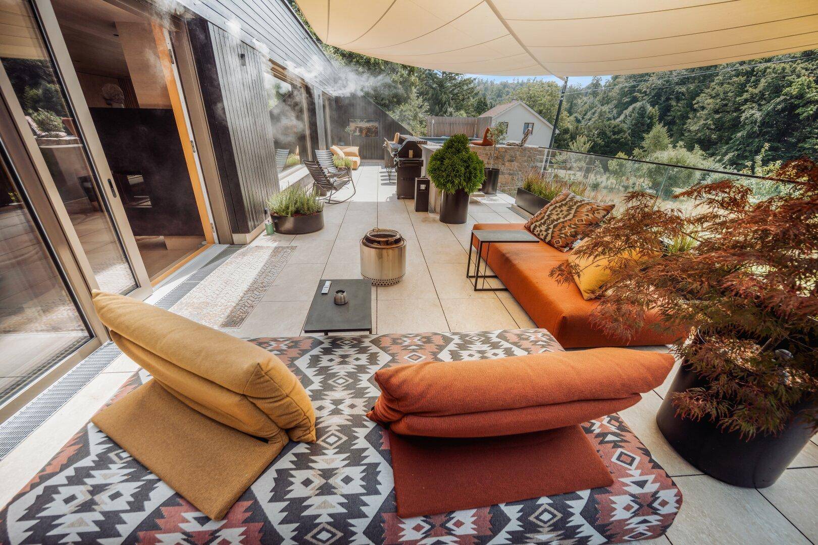 Große Sonnenterrasse mit bequemen Lounge-Möbeln und Blick ins Grüne.