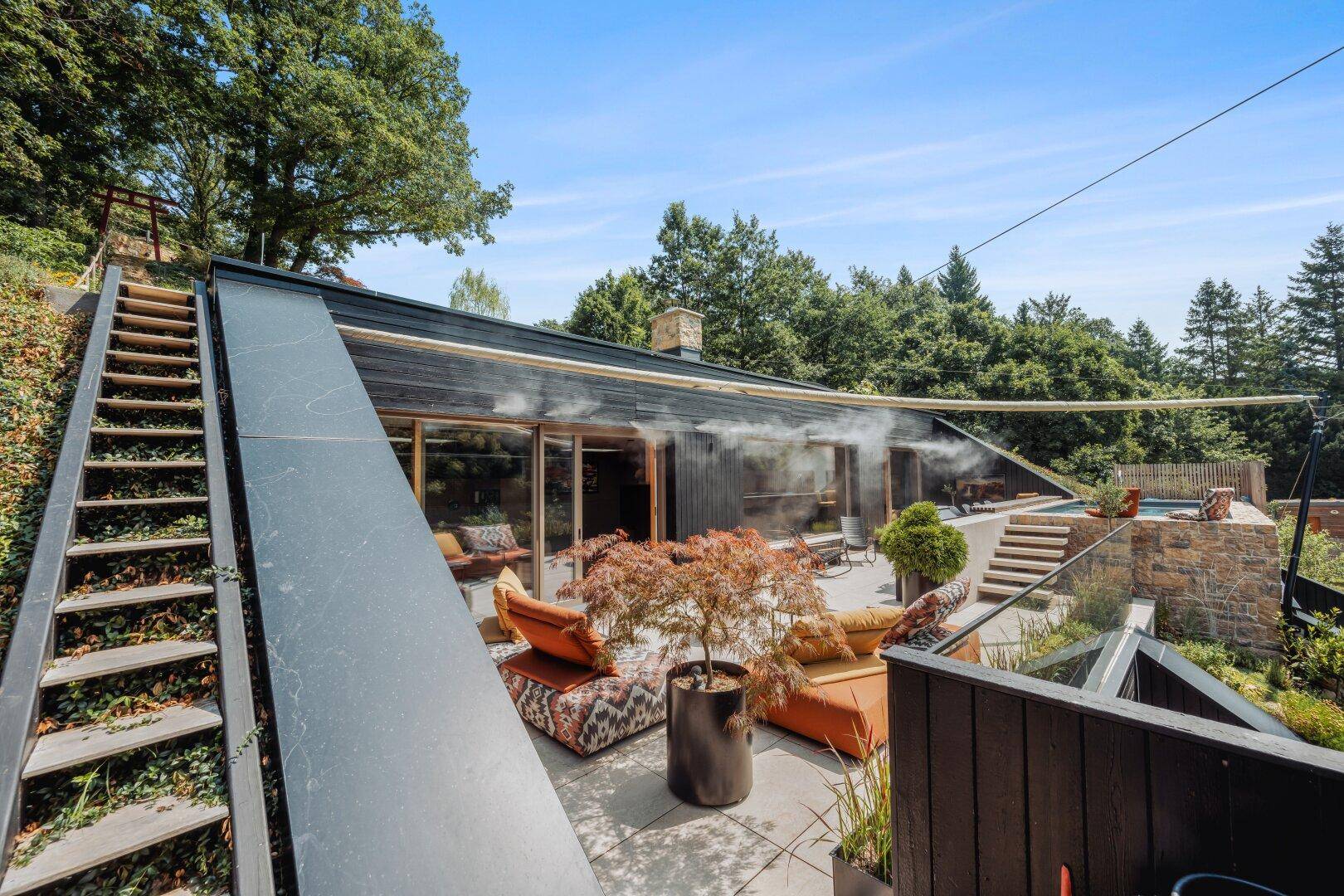 Weitläufige Terrasse mit Außentreppe und Blick auf die bewaldete Umgebung.
