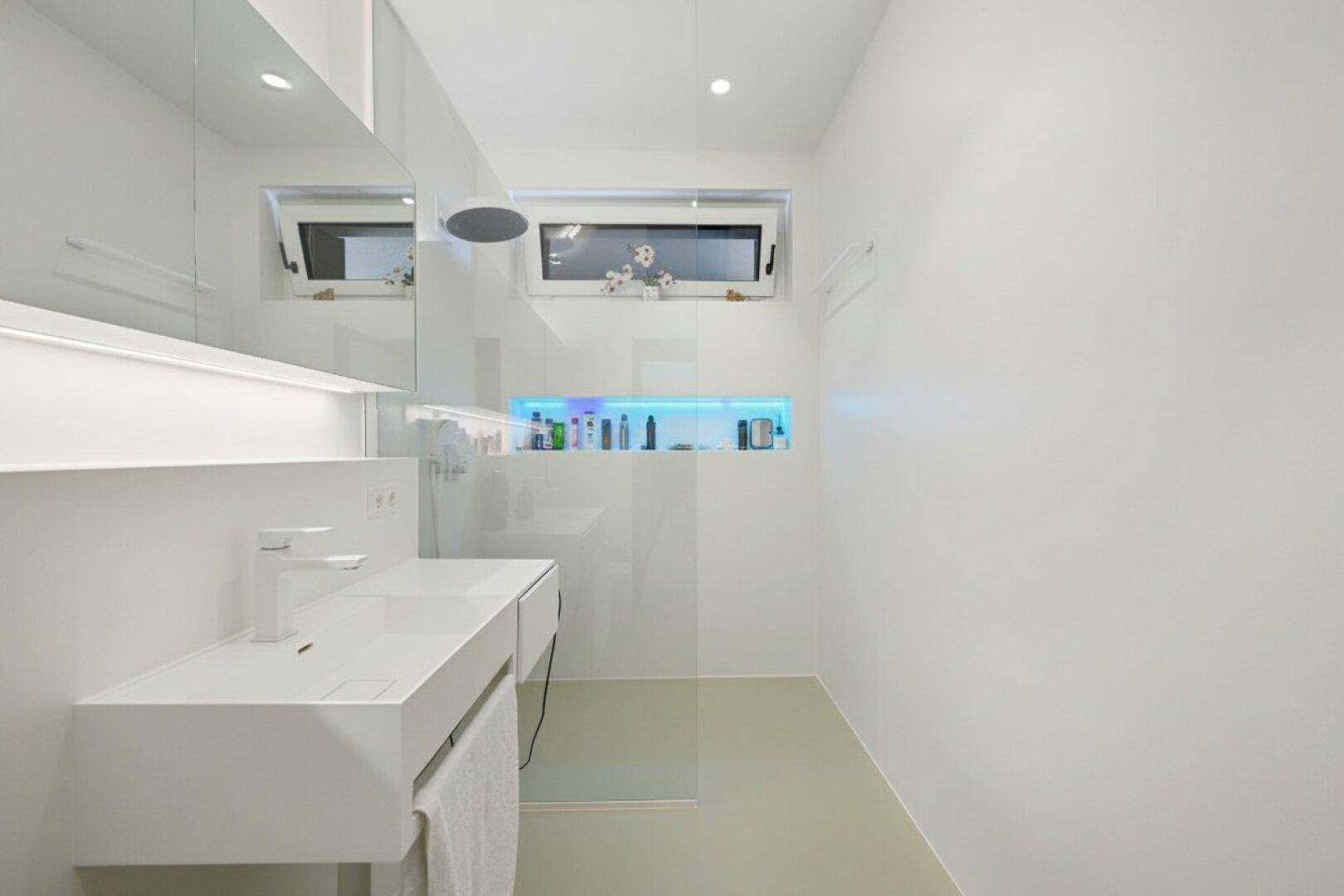 Modernes, weißes Badezimmer mit minimalistischem Design und Regendusche.