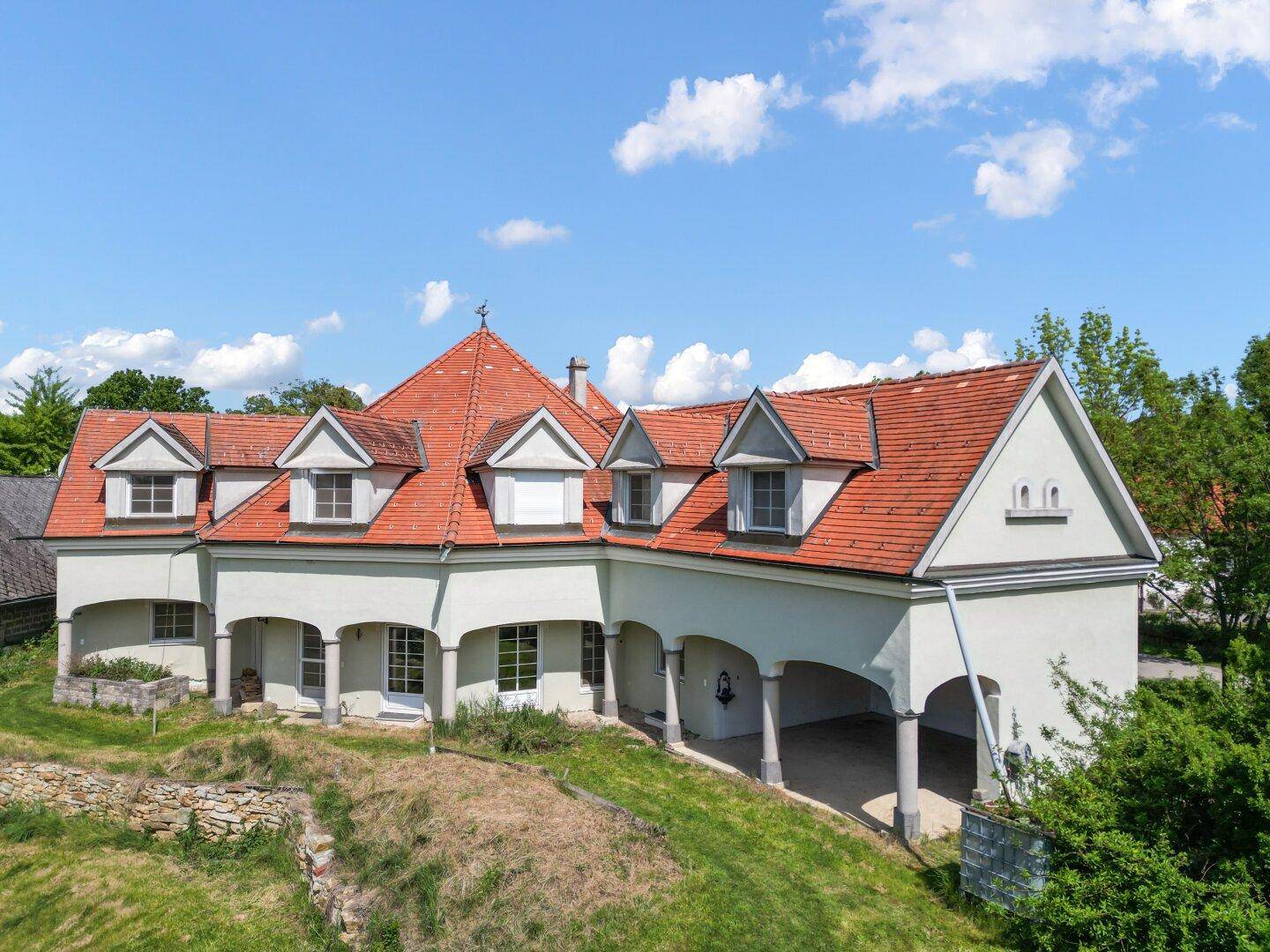 Seitenansicht des Hauses mit mehreren Gauben und weitläufigem Grundstück.