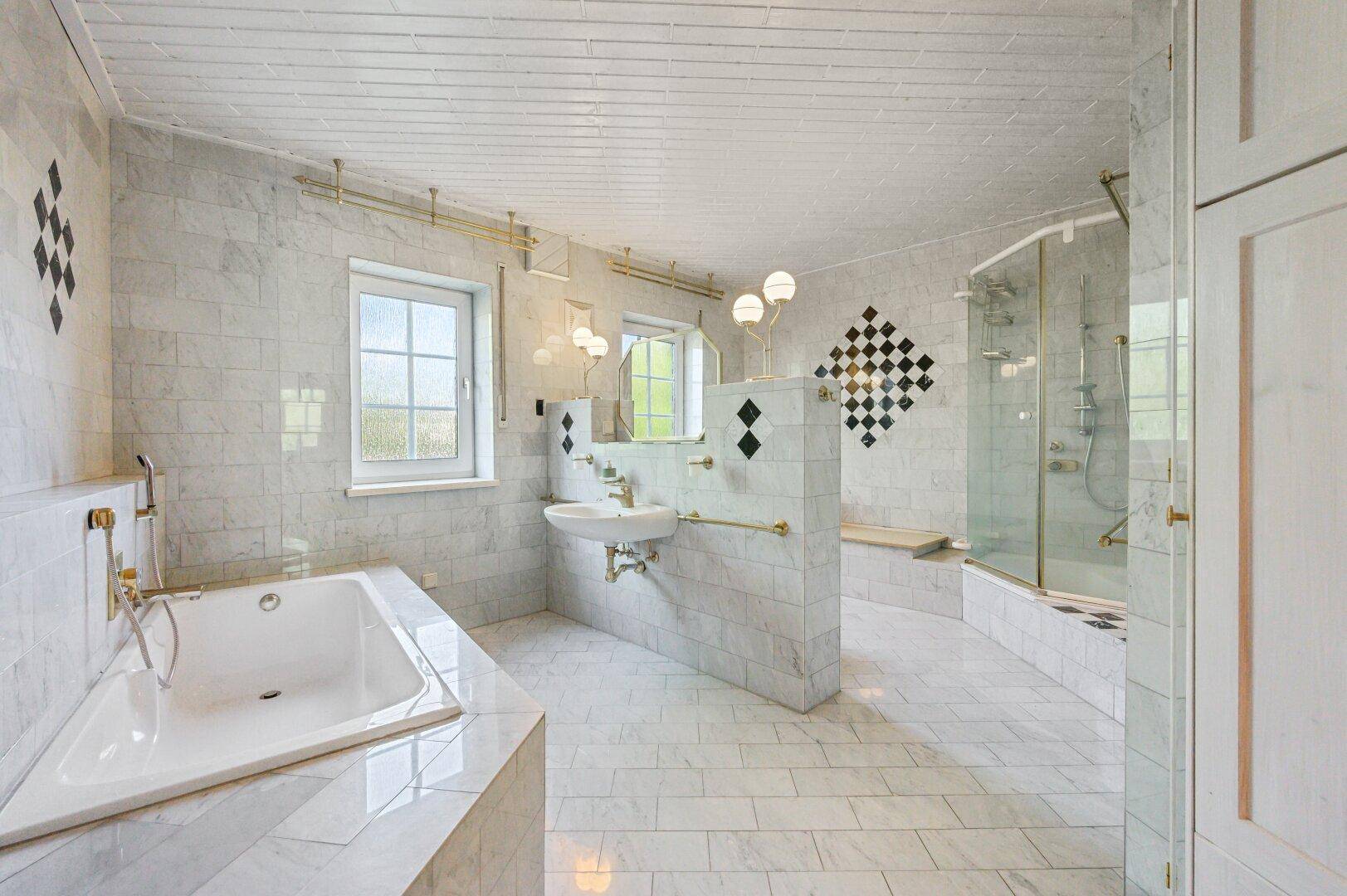 Großes Marmorbad mit Badewanne, Dusche, Doppelwaschbecken und Fenster.