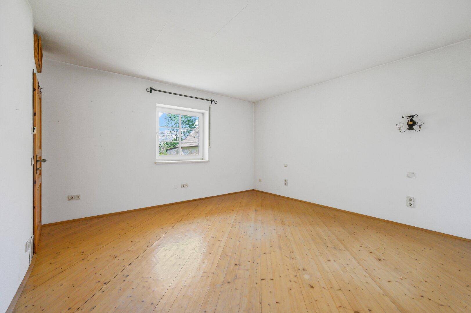 Leeres Schlafzimmer mit Holzboden und einem Fenster.