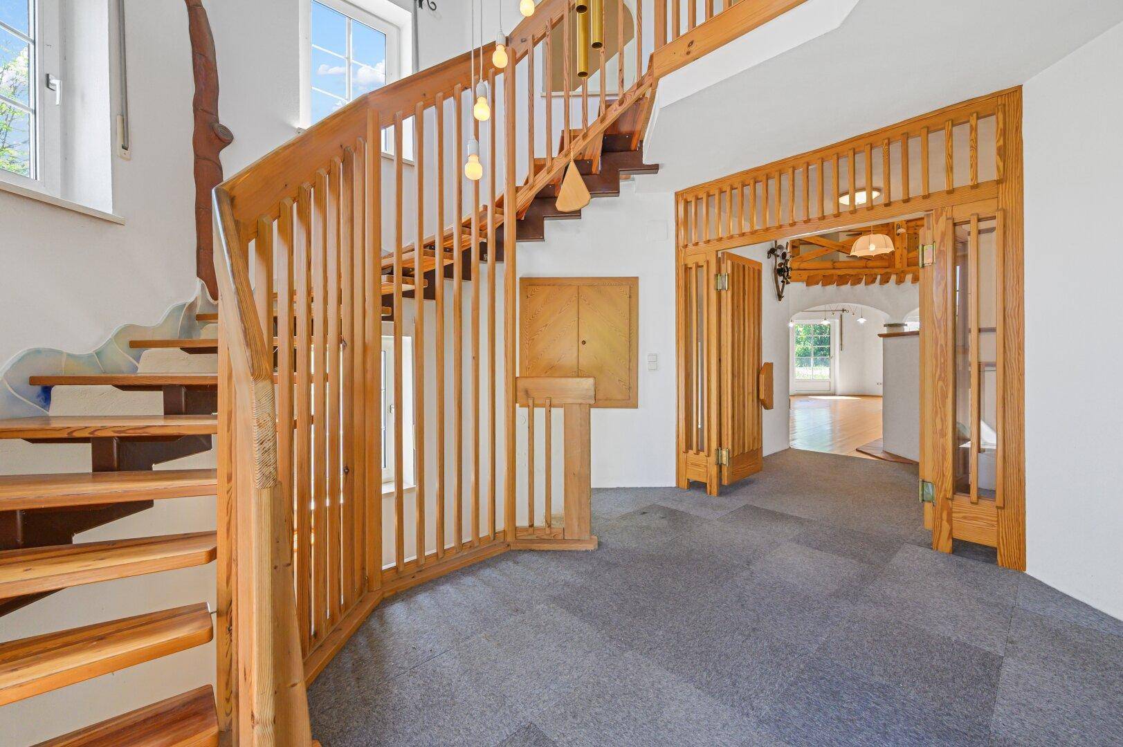 Eingangsbereich mit Holztreppe, Teppichboden und Holztüren.