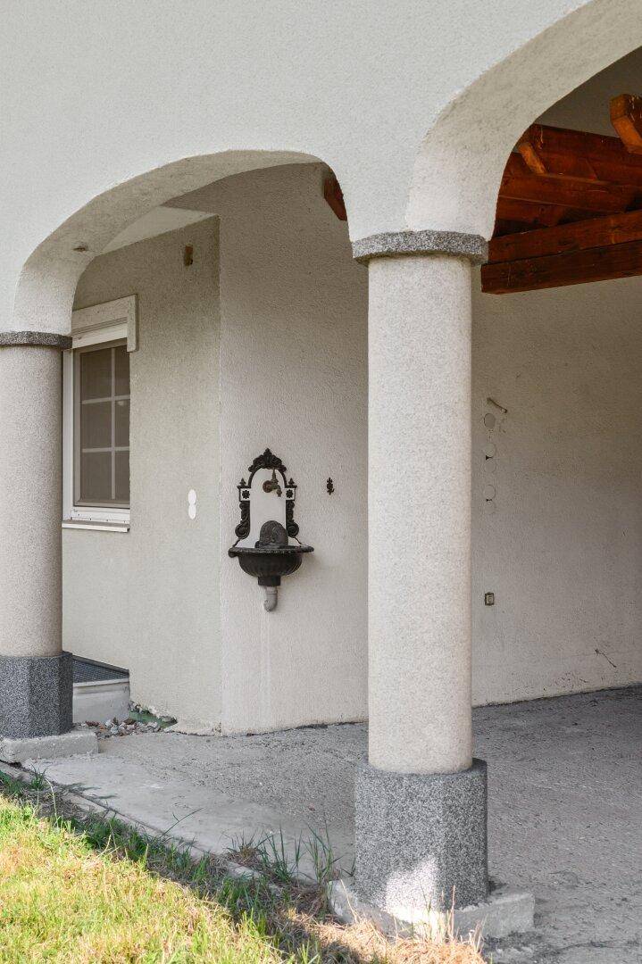 Eingangsbereich mit Rundbögen, Säulen und einem dekorativen Wandbrunnen.