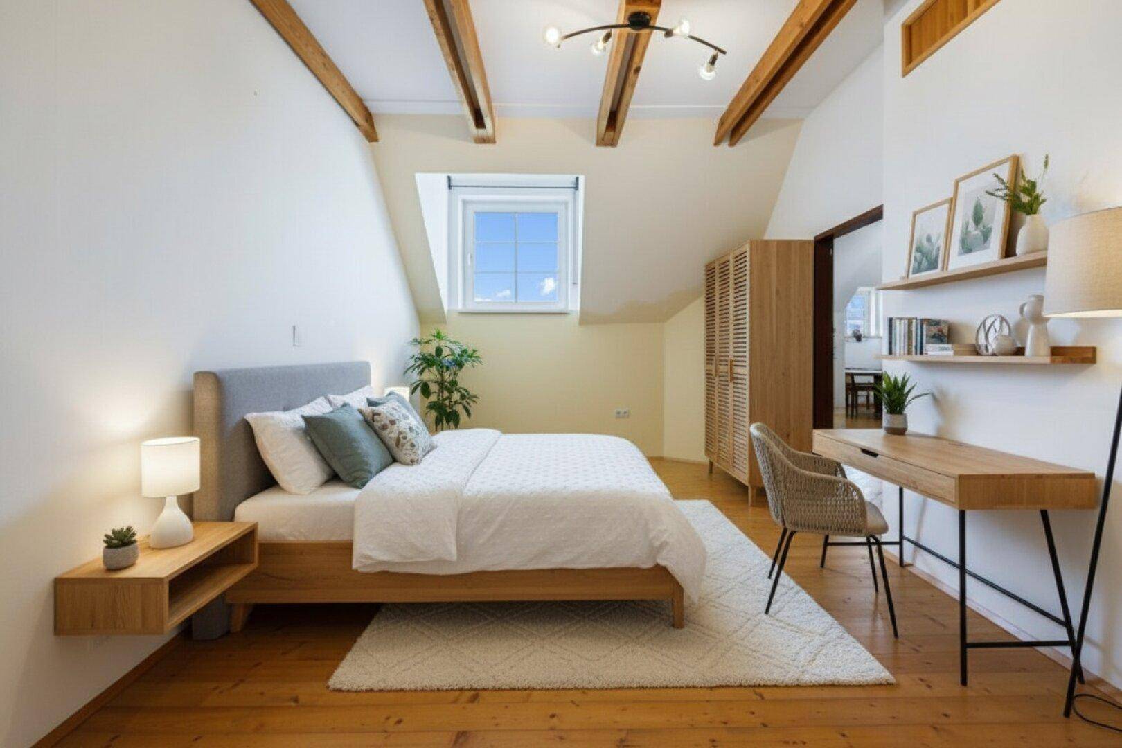 Helles Schlafzimmer mit Holzboden, sichtbaren Deckenbalken und einem Dachfenster.