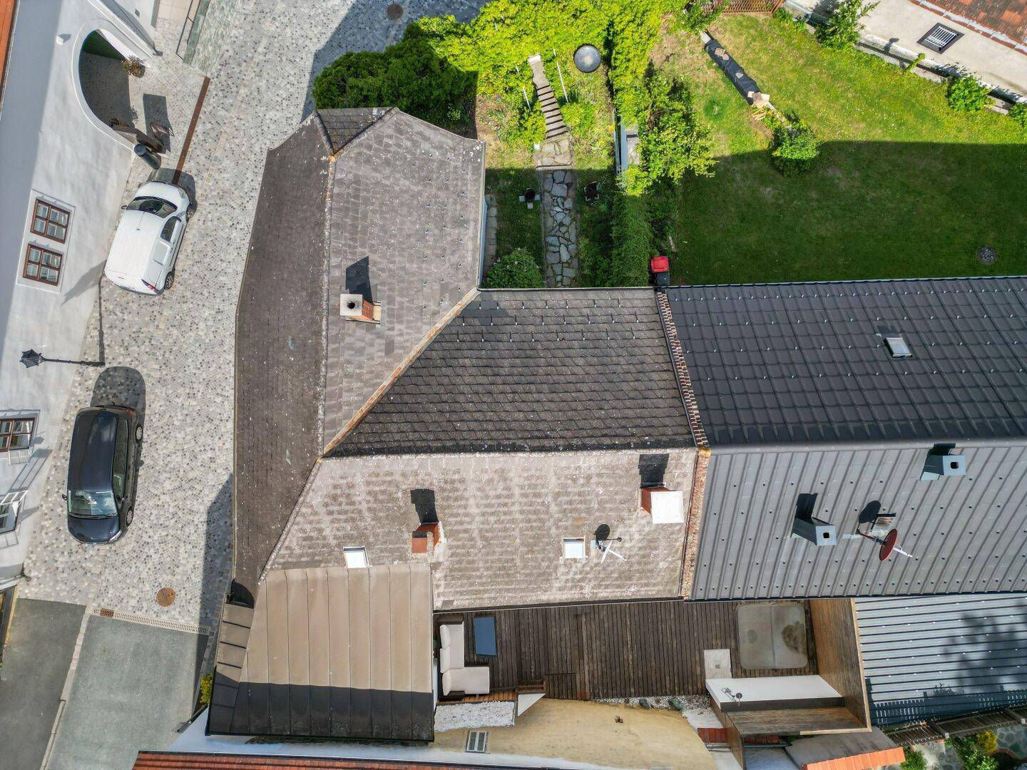 Luftaufnahme der Dächer von historischen Gebäuden und einer gepflasterten Gasse.