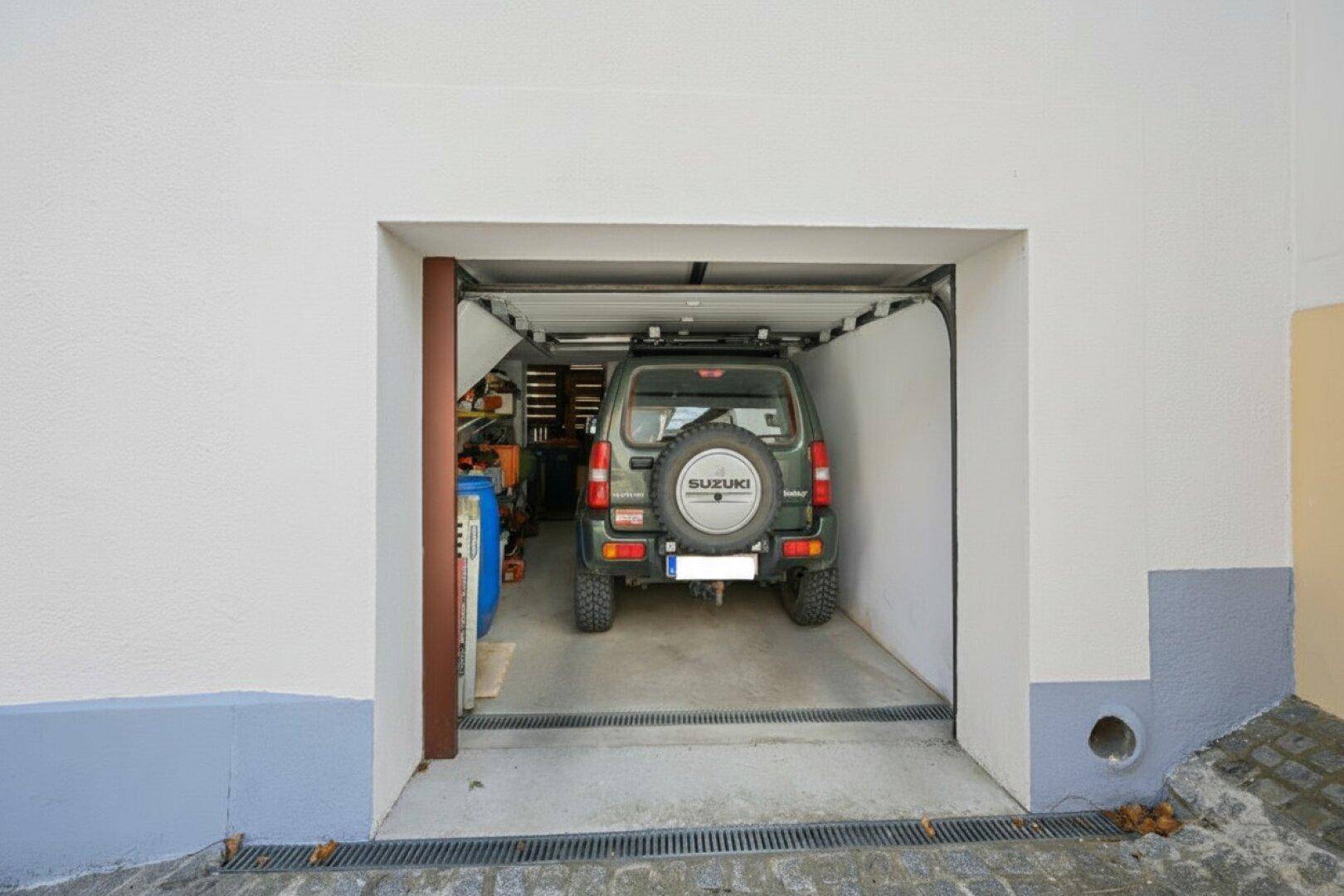 Einzelgarage mit einem Geländewagen und einem praktischen Rolltor.