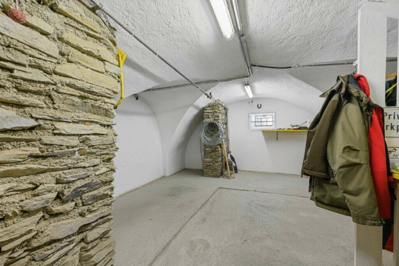 Geräumiger Gewölbekeller mit unverputzter Steinwand und praktischer Lagerfläche.