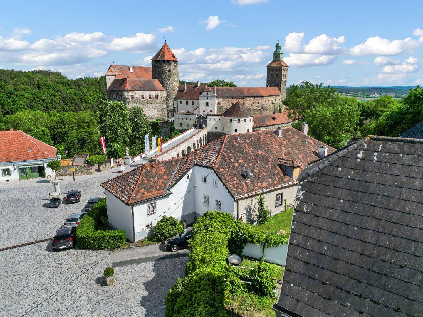 Panoramablick auf eine historische Burg und die umliegende Stadt mit traditionellen Dächern.