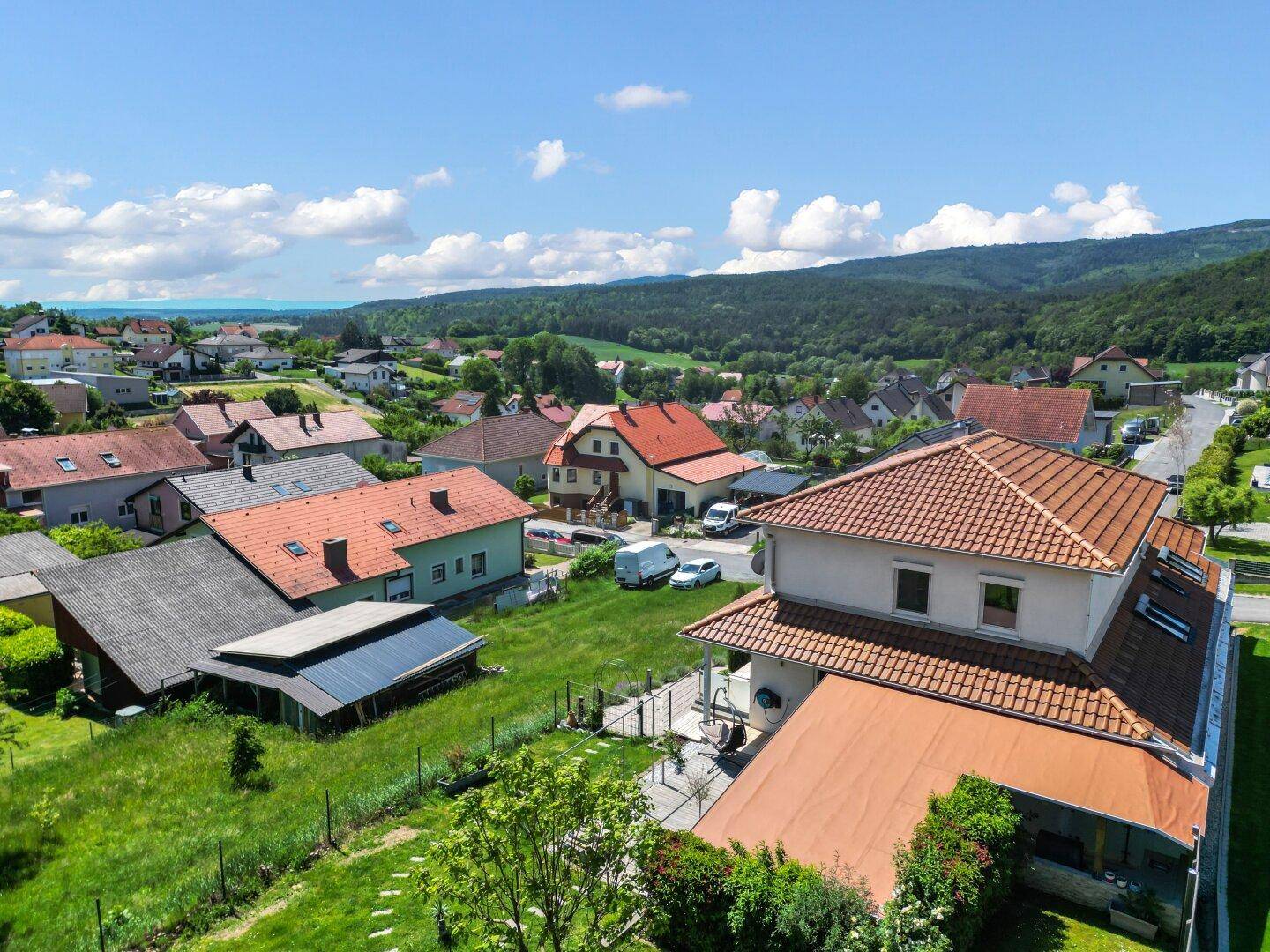Panoramablick auf die ländliche Umgebung mit Wohnhäusern und grünen Hügeln.