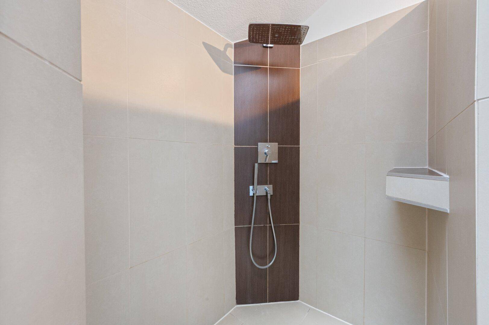 Moderne Duschkabine mit Regendusche und eleganten Fliesen in warmen Farbtönen.