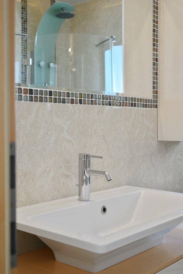 Nahaufnahme des modernen Einzelwaschbeckens mit Armatur und Spiegel im Badezimmer.