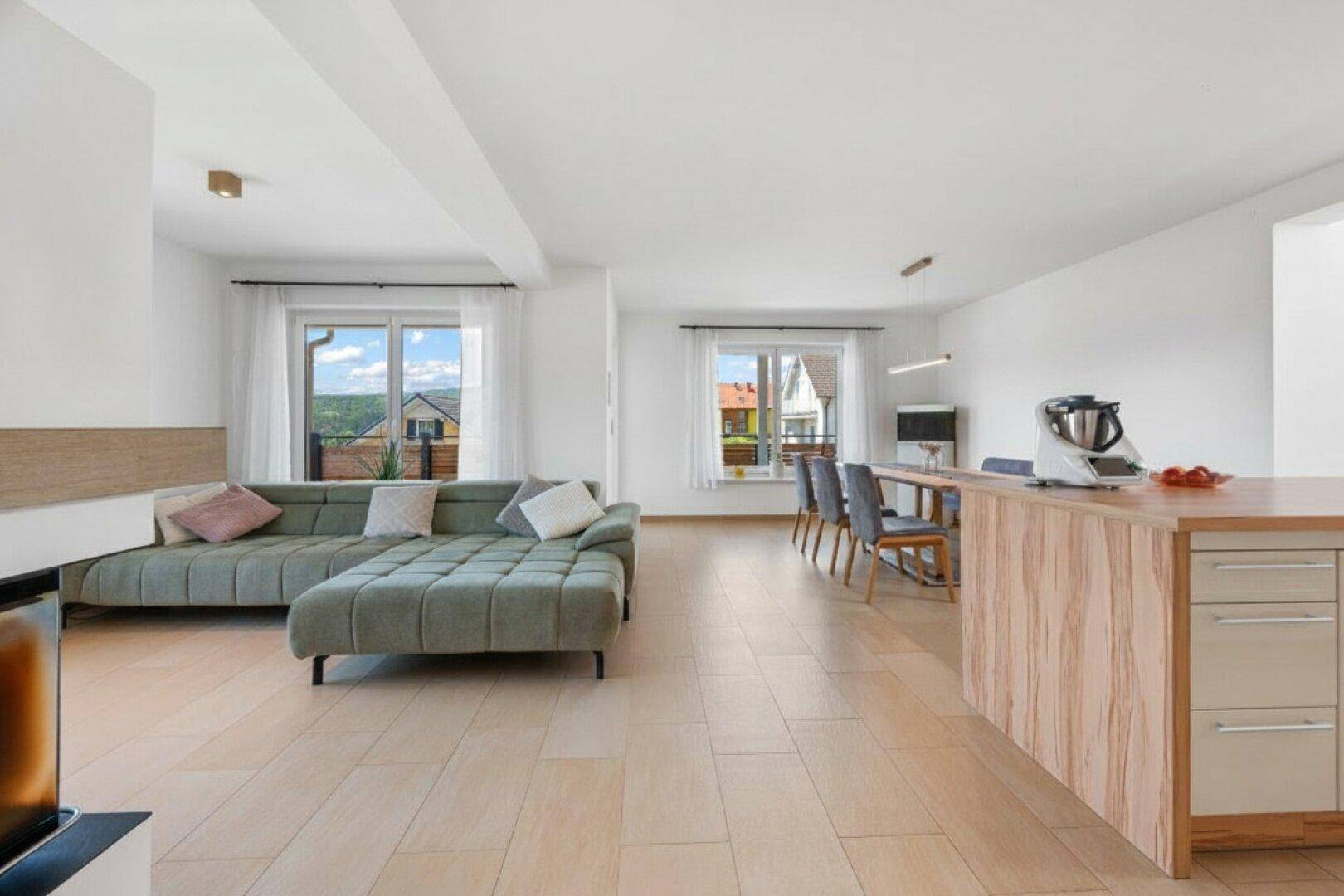 Heller offener Wohn- und Essbereich mit moderner Einrichtung und Zugang zum Balkon.
