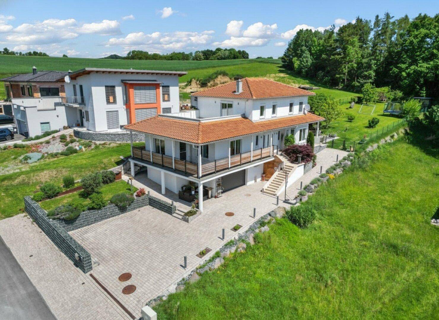 Großzügiges Einfamilienhaus mit weitläufigem Grundstück und Blick auf die grüne Landschaft.