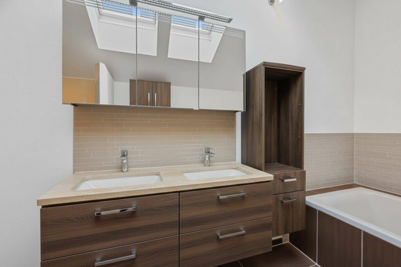 Geräumiges Badezimmer mit Doppelwaschbecken, Badewanne und viel Stauraum.